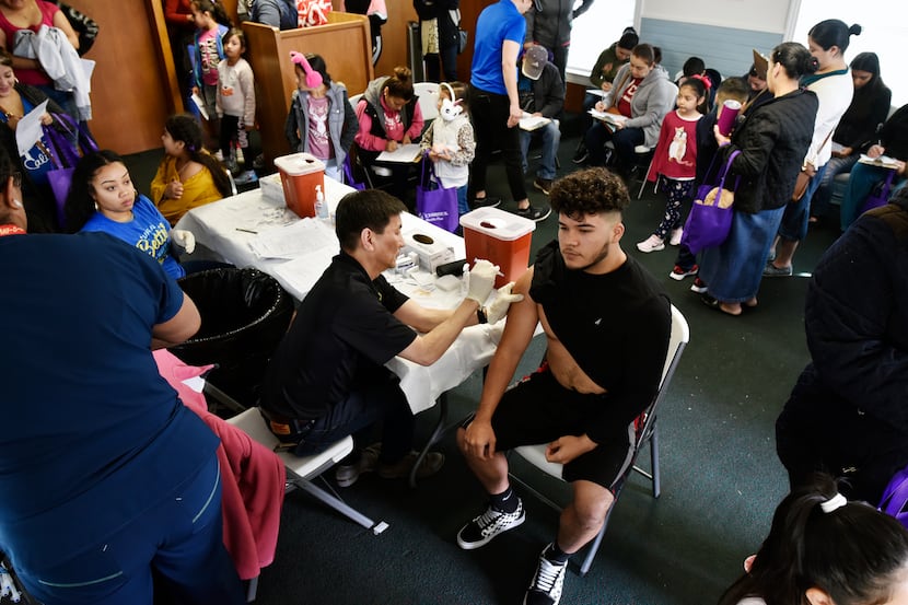 Dr. Philip Huang, director of the Dallas County Health Department, distributes a flu vaccine...