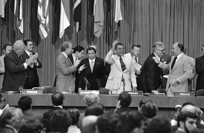 President Jimmy Carter applauds as General Omar Torrijos waves after the signing and...