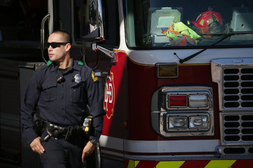 A Dallas police officer walks by Dallas Fire-Rescue ladder 19 outside of the Baylor...