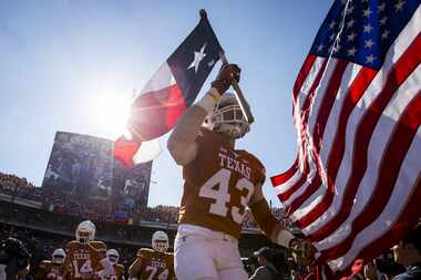 Texas tight end Logan Mills (43) carries the Texas flag as he leads the team onto the field...
