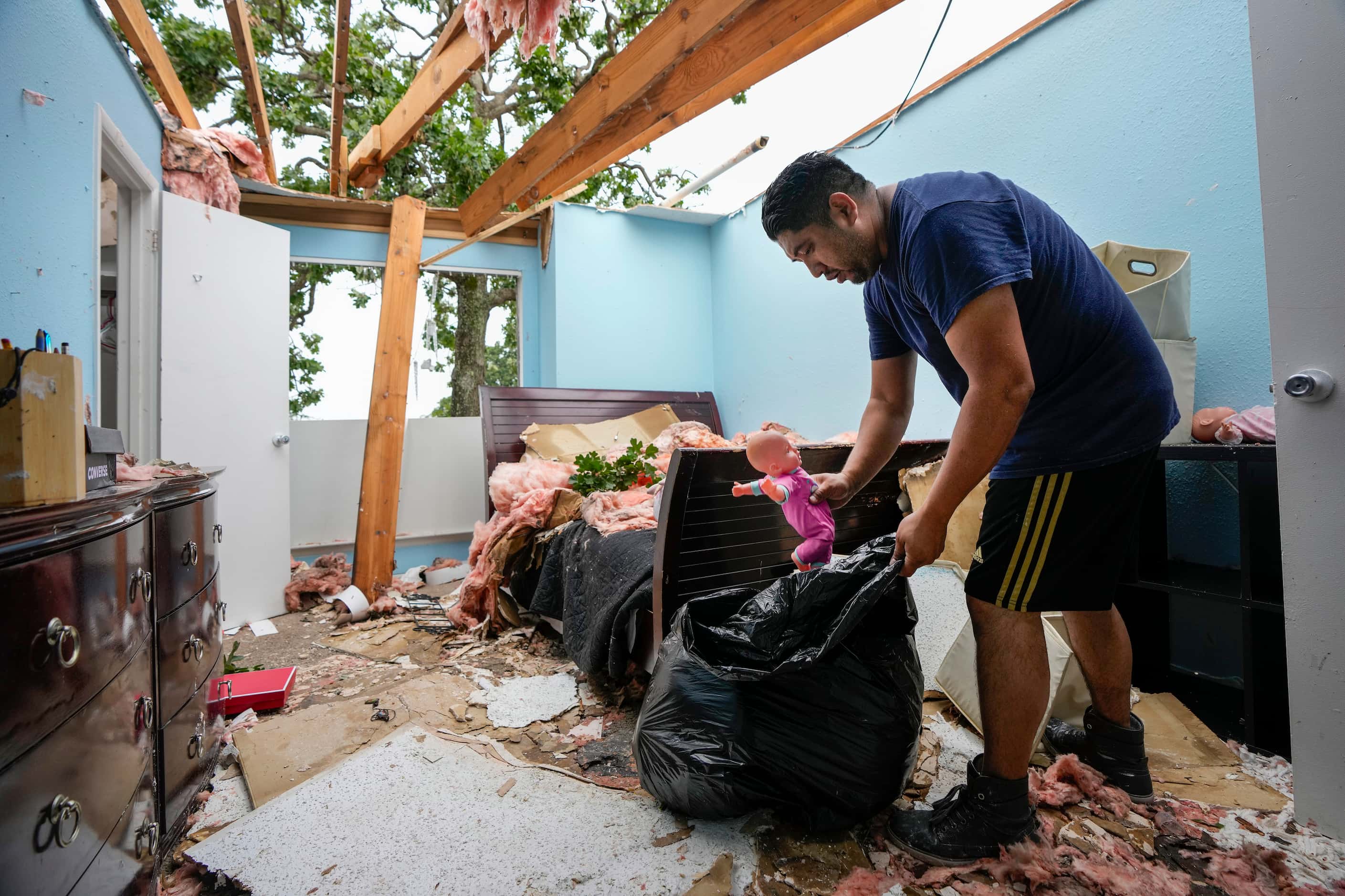 Juan Angeles, left, cleans out a bedroom in his apartment in the aftermath of a severe...