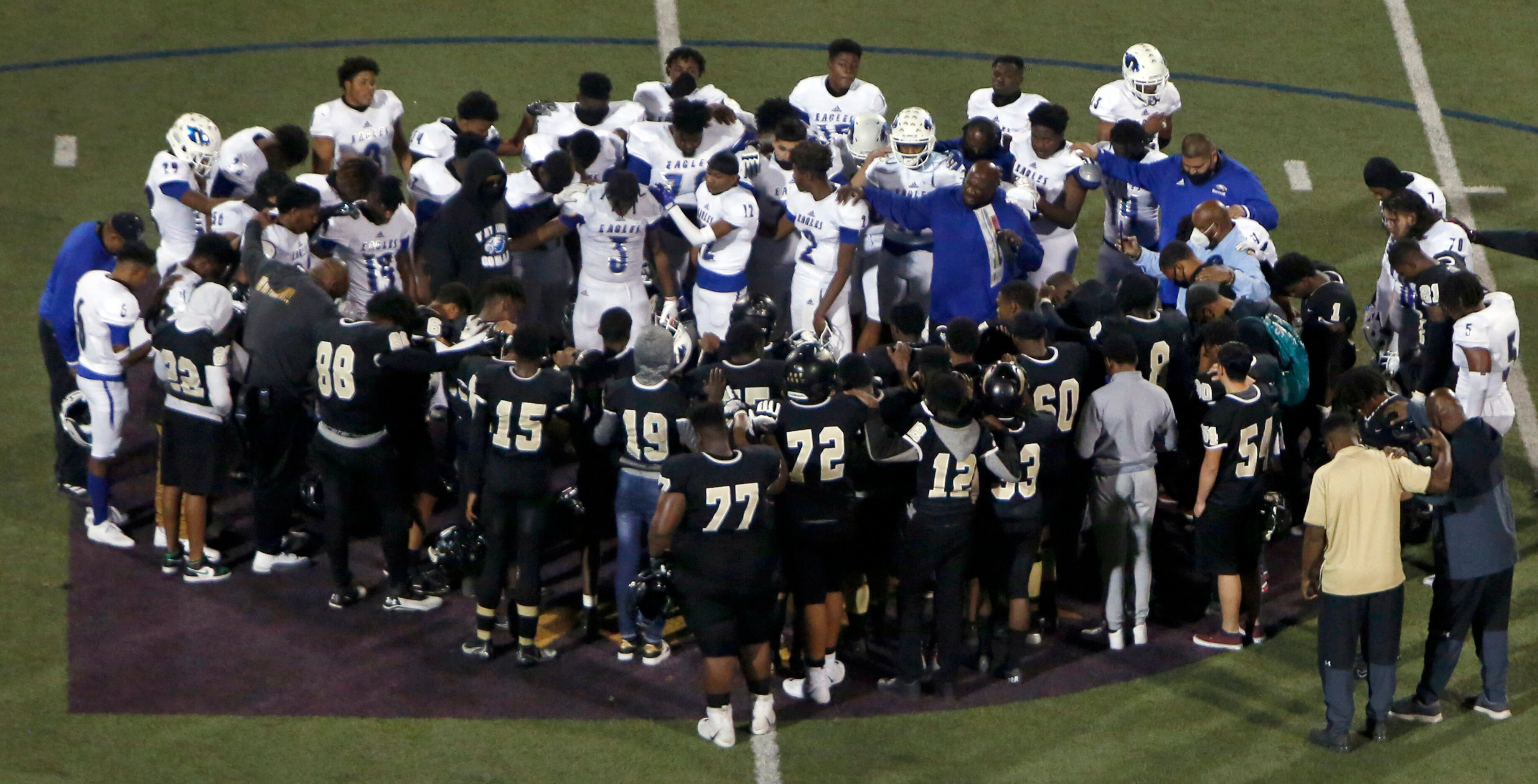 Wilmer Hutchins head coach Elzie Barnett Sr., center right, leads a prayer as his team is...