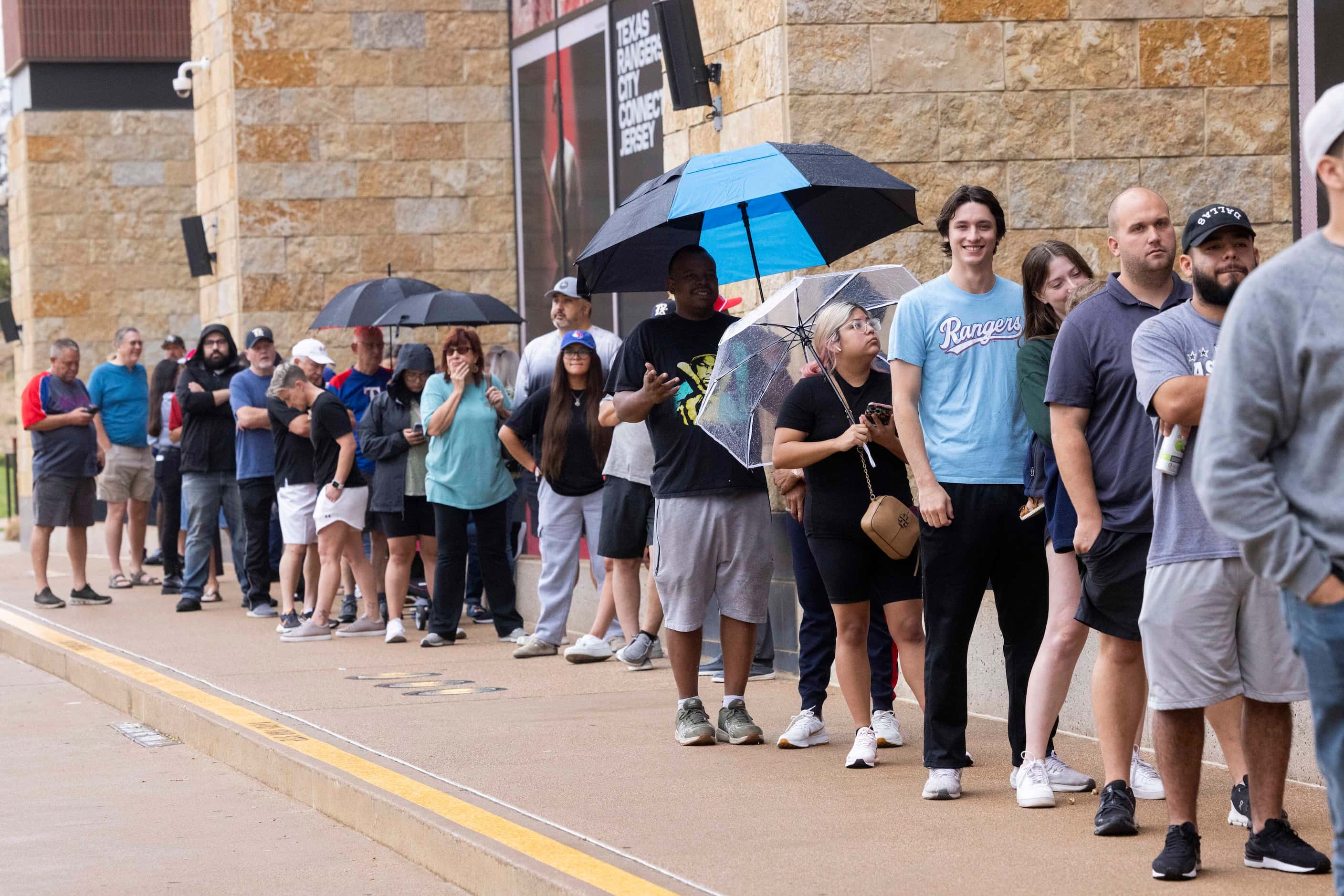 Fans wait for the Grand Slam Team Store at Globe Life Field to open in Arlington on Tuesday,...