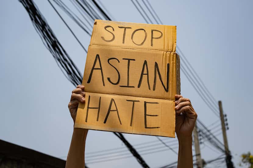 Hands hold up a cardboard sign that reads Stop Asian Hate in all capital letters.