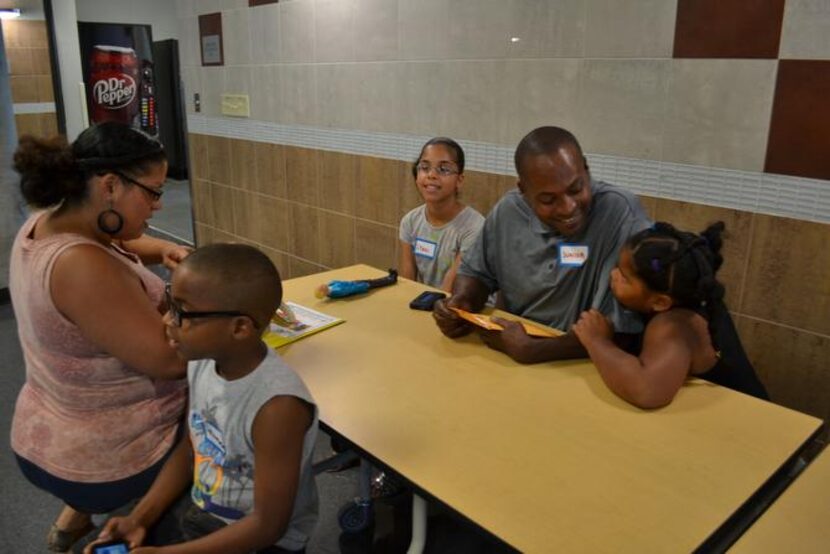 
Yasmine Campos (far left) fills out enrollment forms for her 7-year-old daughter, Jaelene...