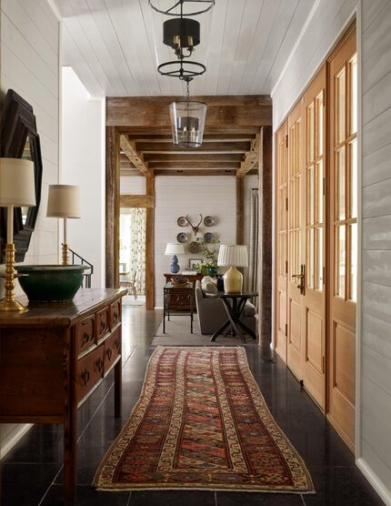 Pattered runner on dark floor in home's front hallway with buffet