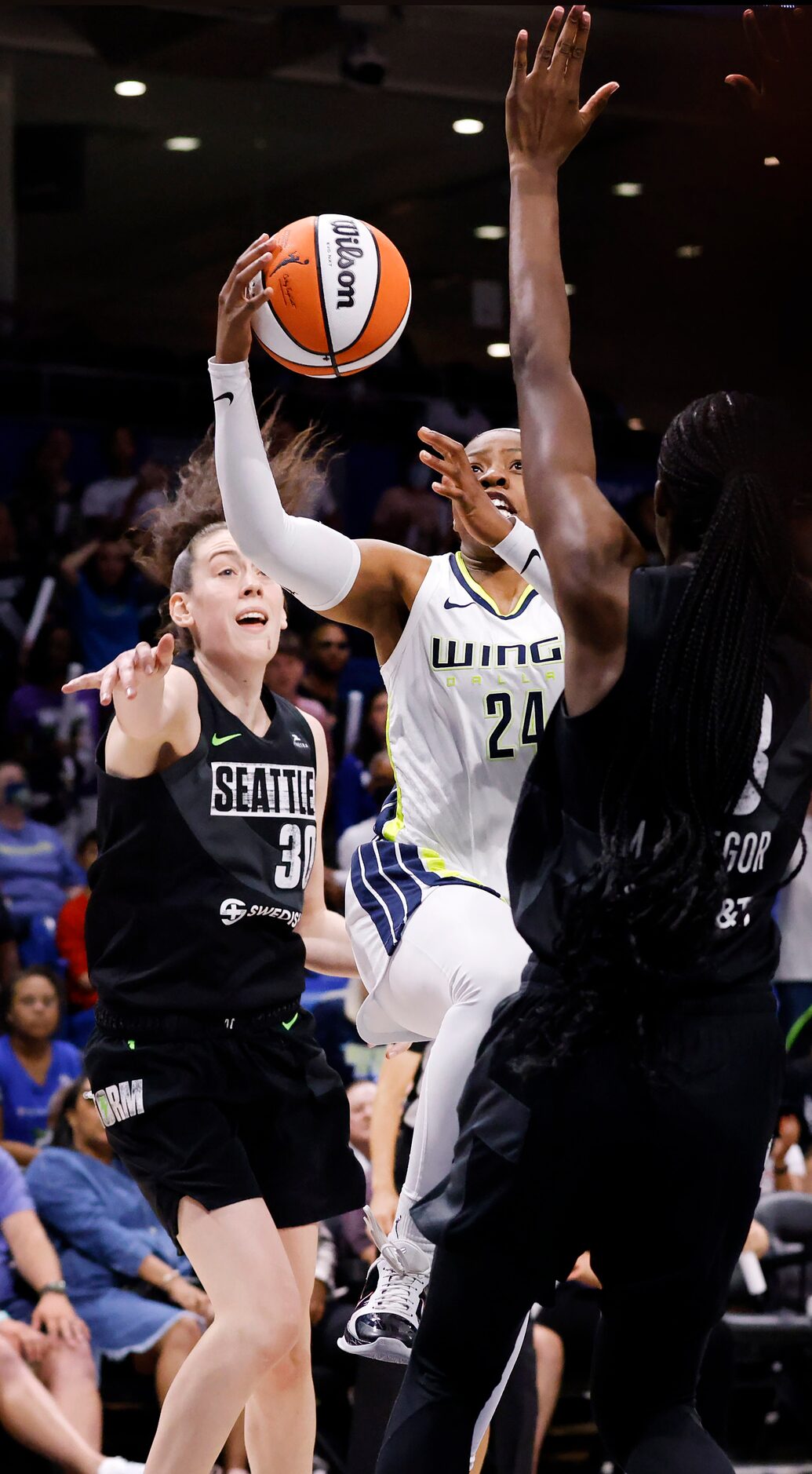 Dallas Wings guard Arike Ogunbowale (24) splits Seattle Storm center Ezi Magbegor (13) and...