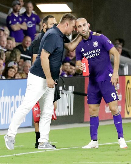 Orlando City interim head coach Bobby Murphy, left, talks to forward Justin Meram (9) during...