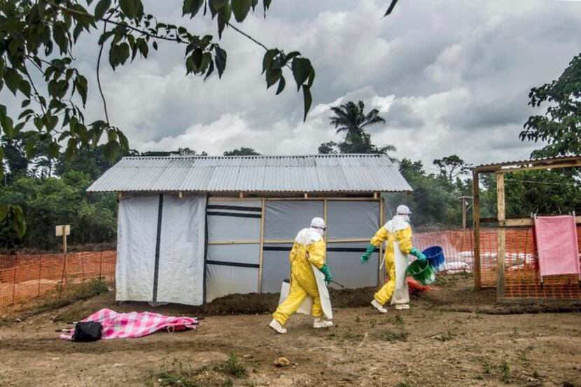 
Health workers prepare to transfer the body of an Ebola victim to the morgue in Kailahun,...