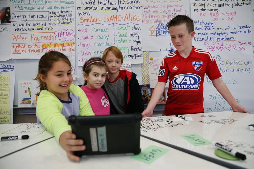 Students take a selfie with a tablet after working on a mathematics equation in a third...