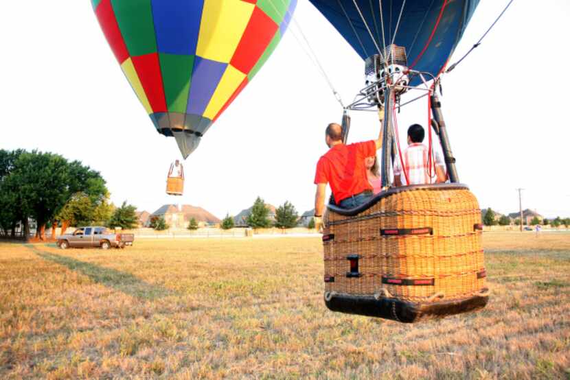 Luc Goethals talks to another balloon pilot as they take off from a field in McKinney. Both...