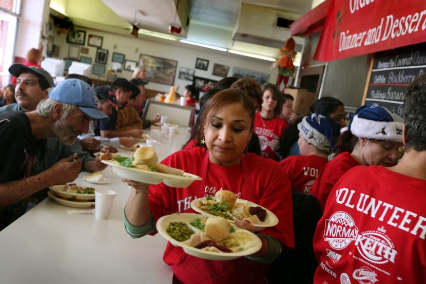 Volunteer Ana Barron, center, carries plates of free food to customers at Norma's Cafe in...