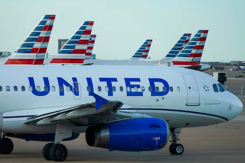 A United Airlines A319 taxis past American Airlines planes at the gates of Terminal C at DFW...