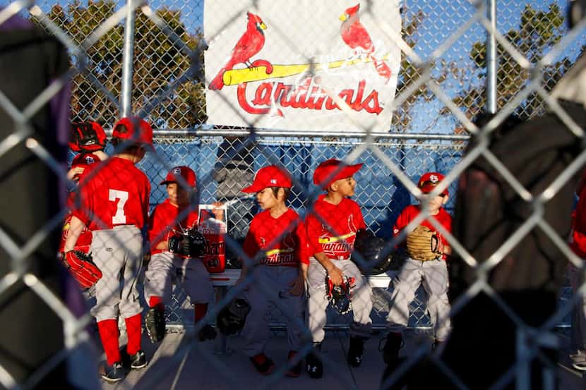 
Young T-ball players from Farmers Branch and Carrollton wait on the bench for the start of...