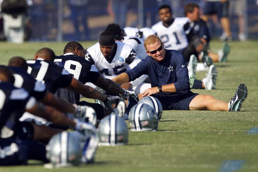 Dallas Cowboys head coach Jason Garrett stretches with his players at the end of afternoon...