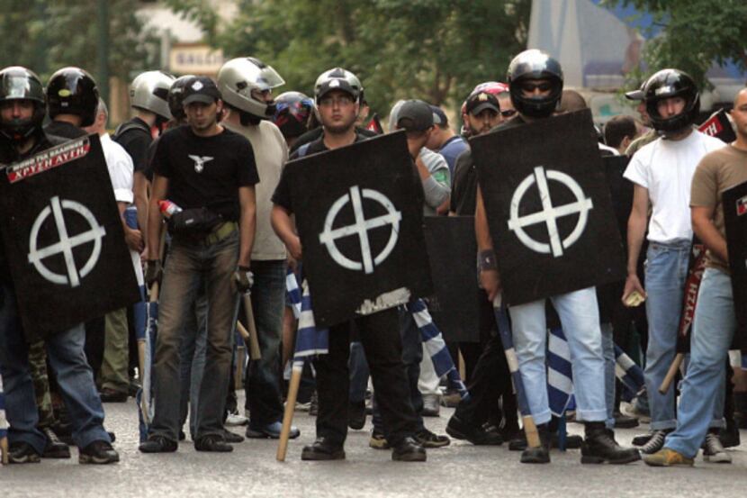 Extreme right-wing group Chryssi Avgi (Golden Dawn) members hold Greek flags and their...