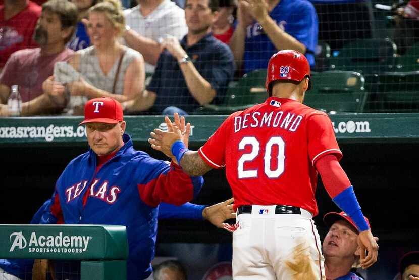 Texas Rangers outfielder Ian Desmond gets a hand from manager Jeff Banister after scoring a...