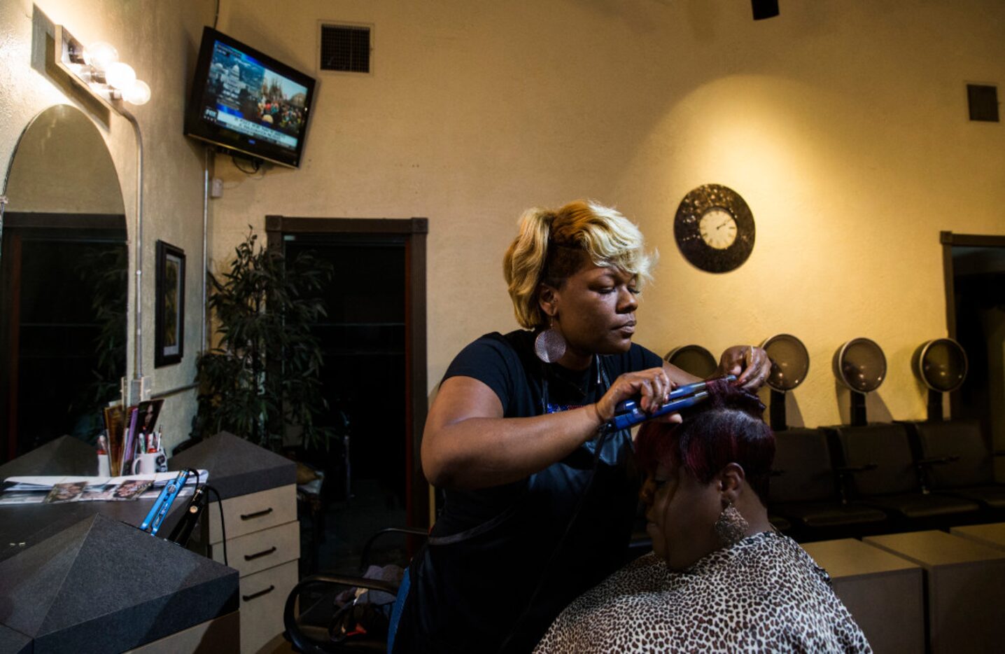 Shannon Gilstrap curls Ericka Davison's hair at Rampage Beauty and Barber Salon across the...