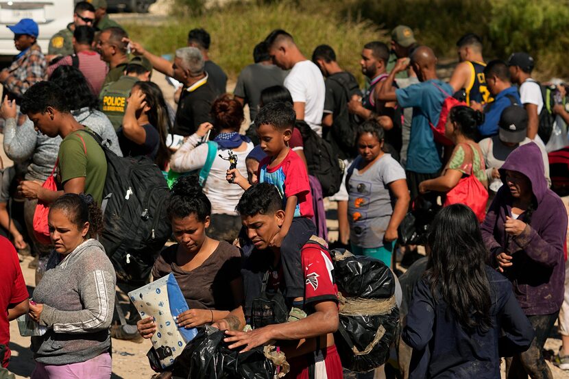 Migrants wait to be processed by the U.S. Customs and Border Patrol after they crossed the...