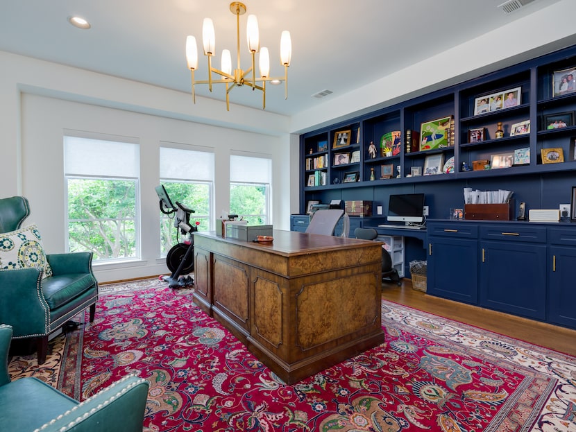 Office with built-in bookcases, patterned rugs, large desk, armchairs