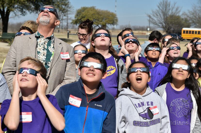 Students look directly at the sun with their eclipse glasses at UNT Discovery Park.