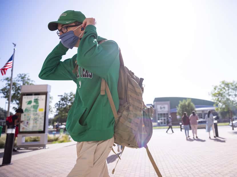 Student Stephen Tykoski puts on his mask before entering the university union during the...