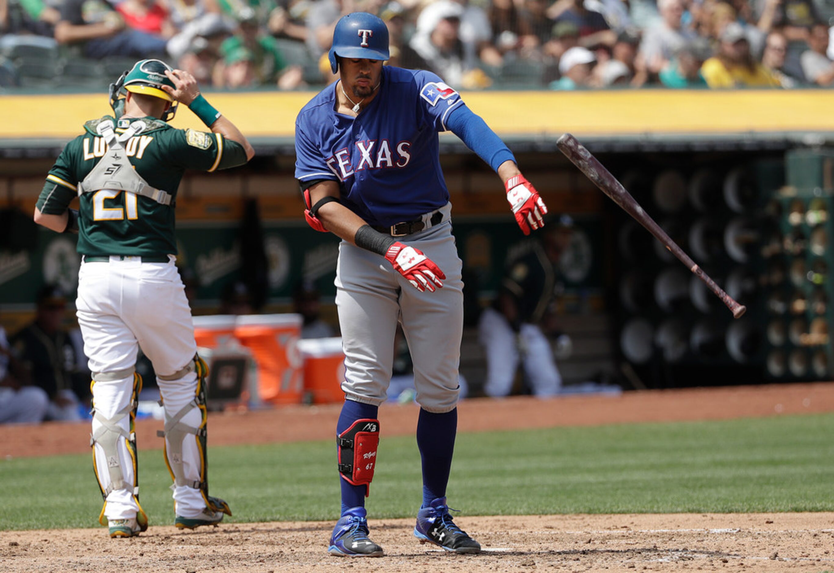 Texas Rangers' Ronald Guzman, right, throws his bat after striking out as Oakland Athletics...