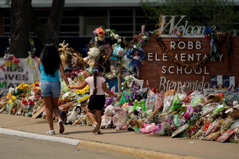 In this July 12, 2022, photo, Visitors walk past a makeshift memorial honoring those killed...