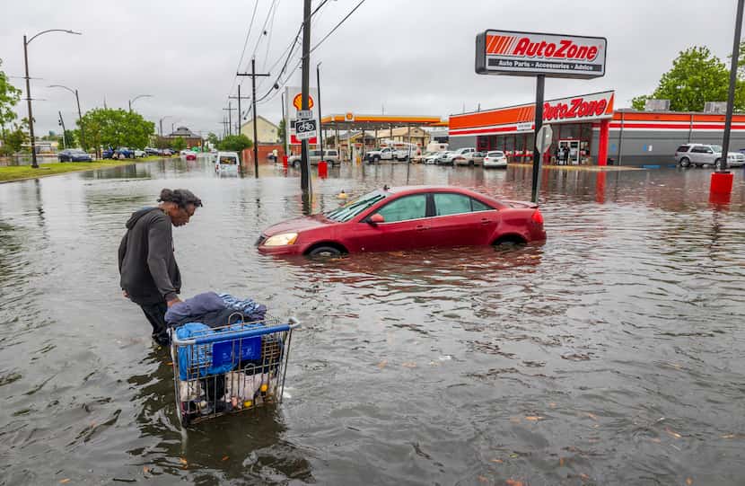 People carry their belongings down a flooded Broad Street in New Orleans, during a severe...