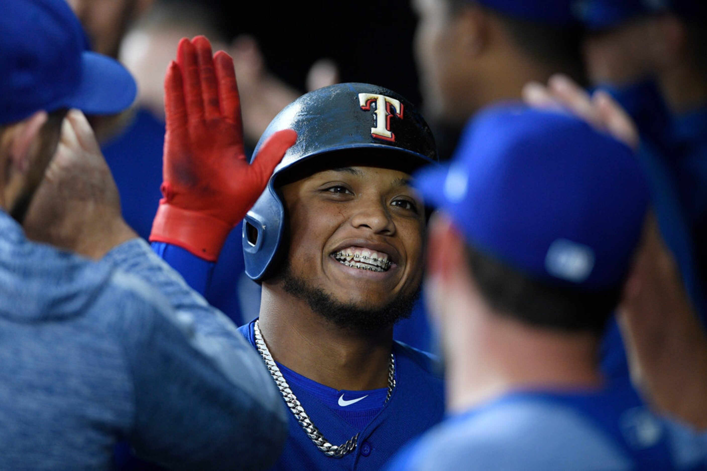 Texas Rangers' Willie Calhoun celebrates his home run in the dugout during the first inning...