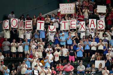 Fans combine to hold up a sign that reads "Come To Texas," while Los Angeles Angels' Shohei...