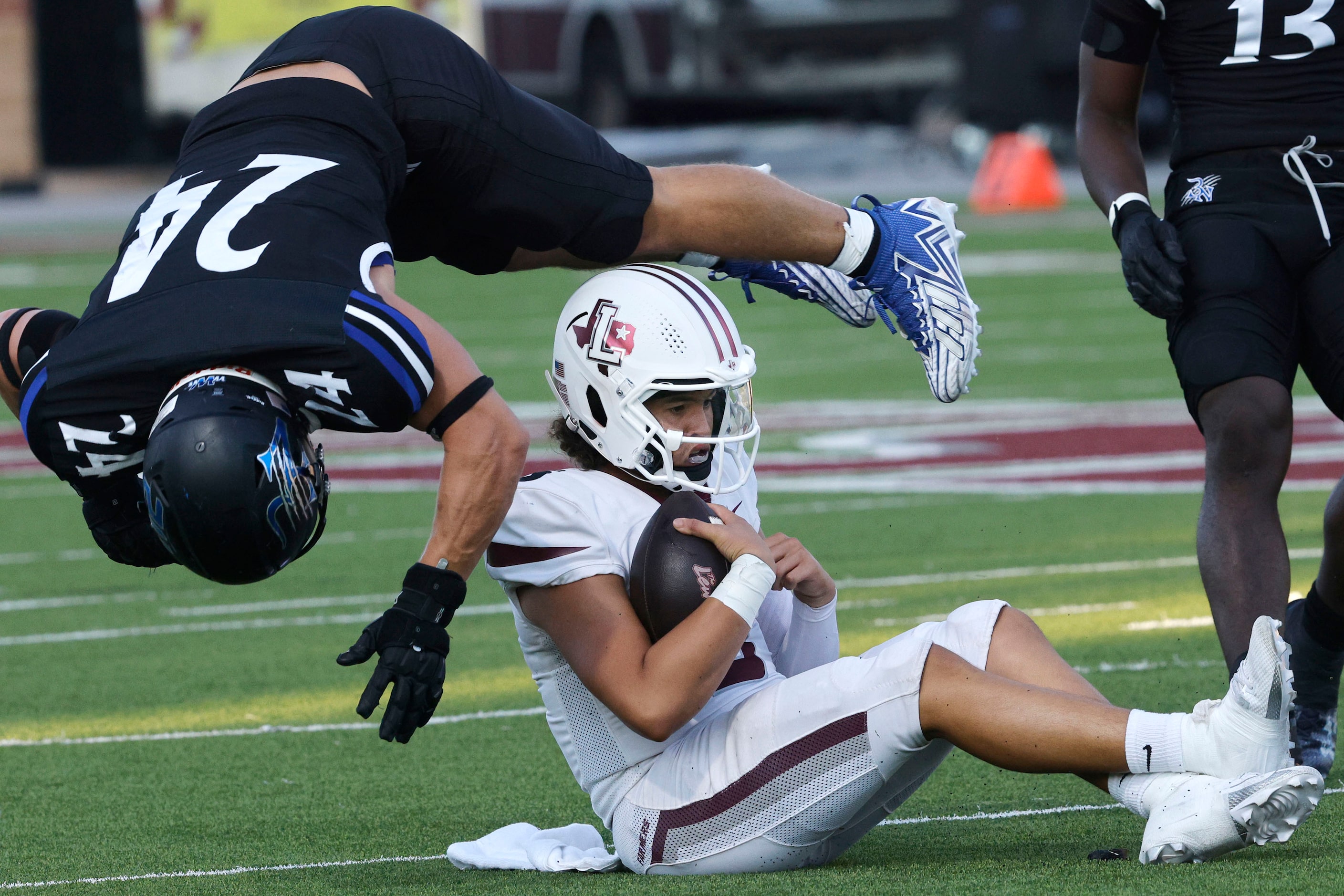 Byron Nelson's Zachary Furnas (24) jumps over Lewisville's quarterback Tre Williams (5)...