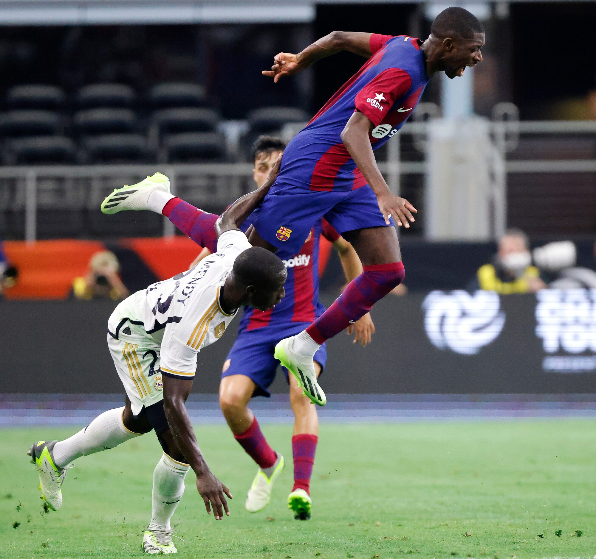 Barcelona forward Ousmane Dembélé (7) goes up and over Real Madrid defender Ferland Mendy...