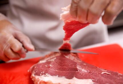 Elson Douangdara trims the fat off of an eye round steak cut at Saap Lao Kitchen, a...