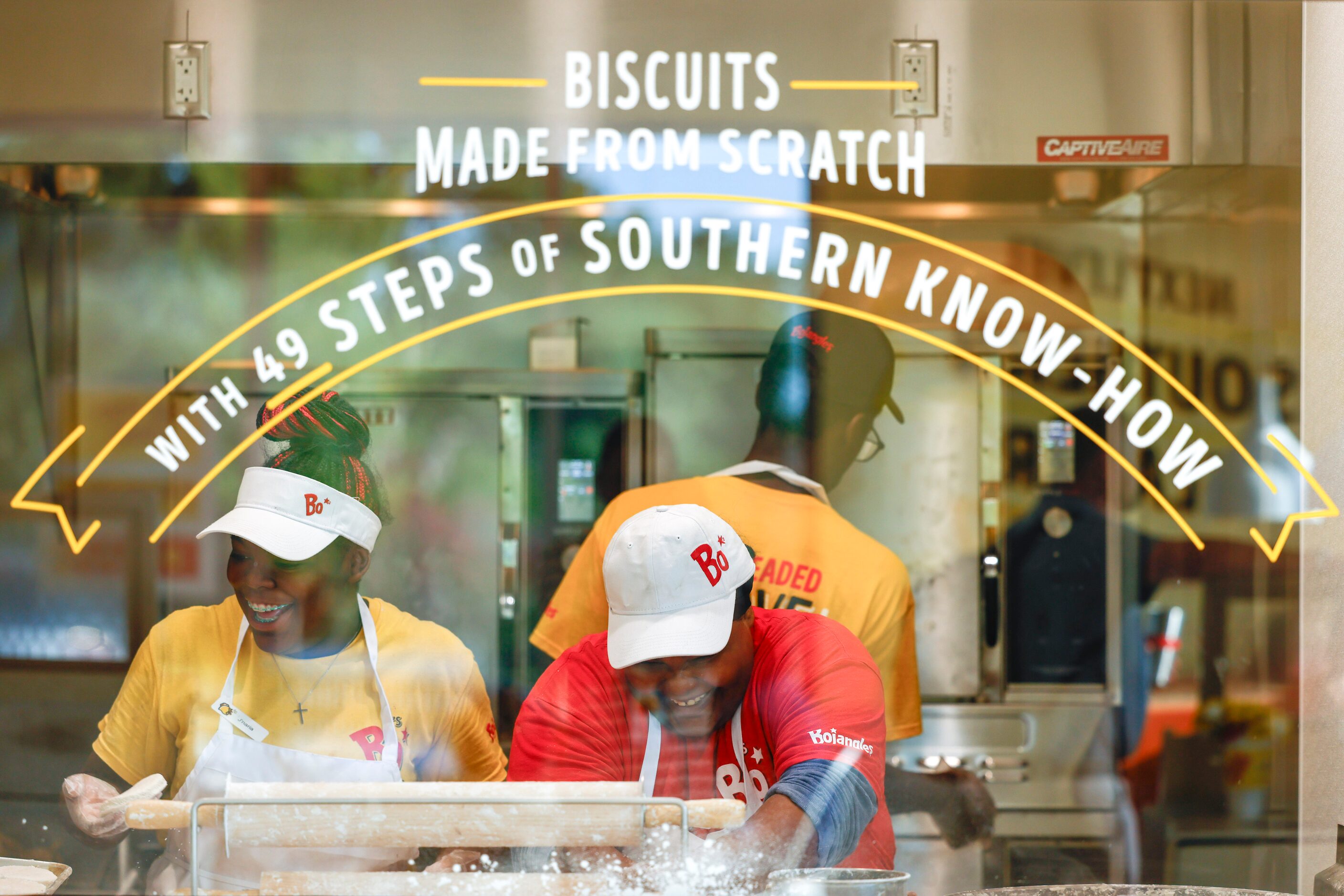 Bojangles employee J’naria Coffey (left) and Shae Mason laugh as they prepare biscuits from...