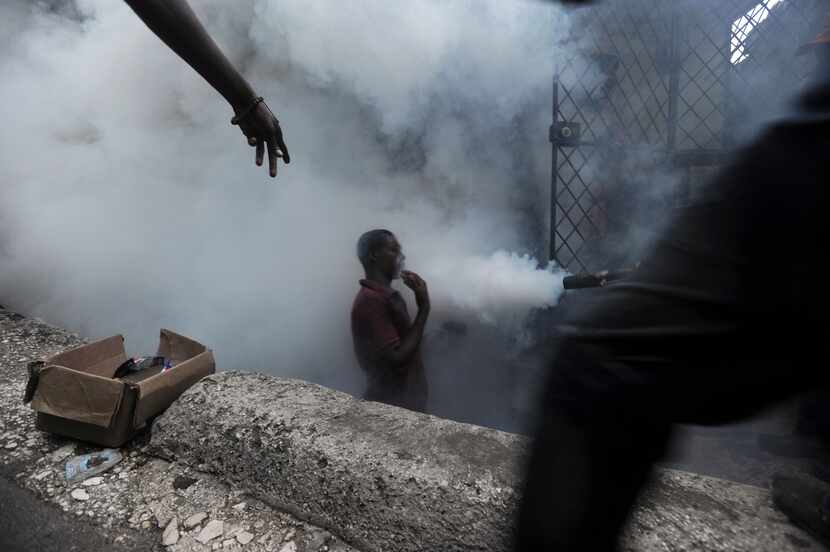  Residents walk amid fumes as workers from Haiti's Ministry of Public Health and Population...