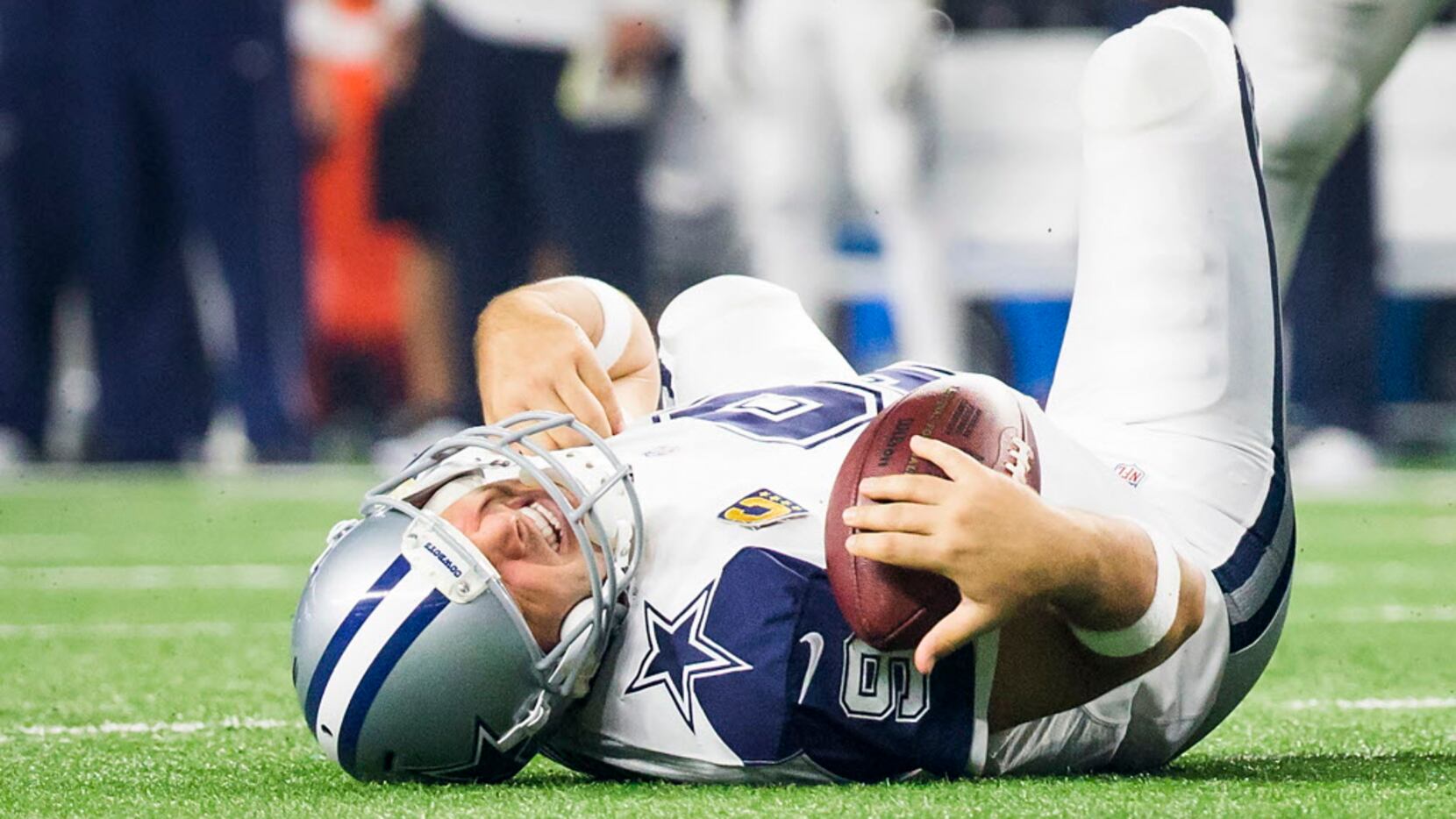 Dallas Cowboys quarterback Tony Romo (9) grimaces as he rests on the turf after being sacked...