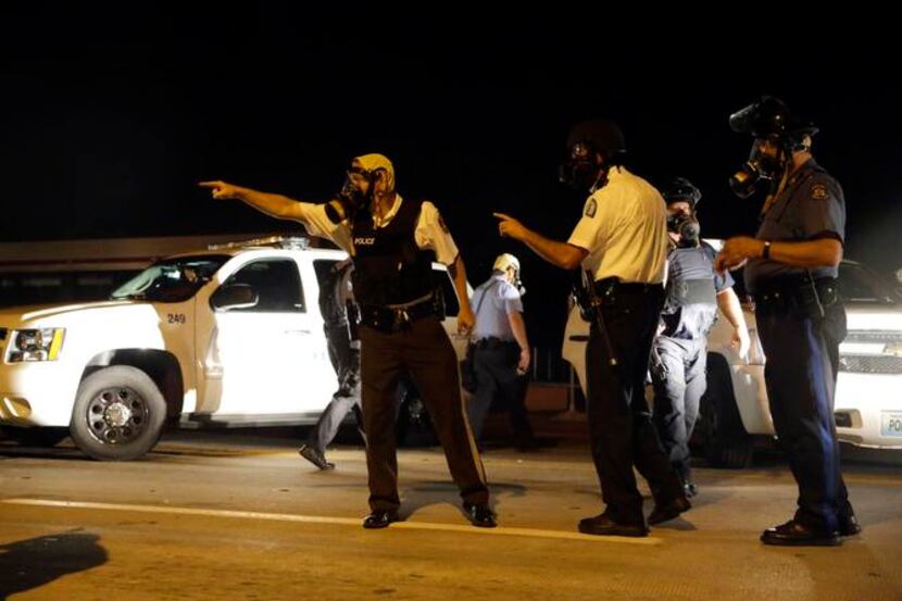
Police take up positions after being shot at Monday in Ferguson, Mo. 
