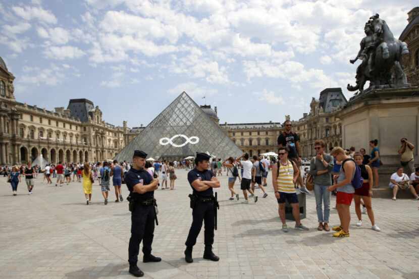 Police officers stand guard at the Louvre in Paris during an August visit by French Interior...