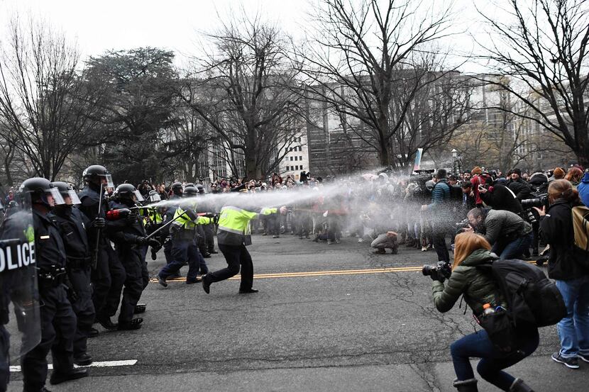 TOPSHOT - Police pepper spray at anti-Trump protesters during clashes in Washington, DC, on...