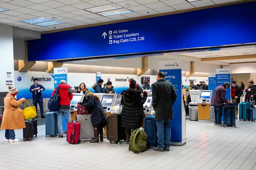 Passengers check their bags at an American Airlines ticket counter at DFW Airport on...