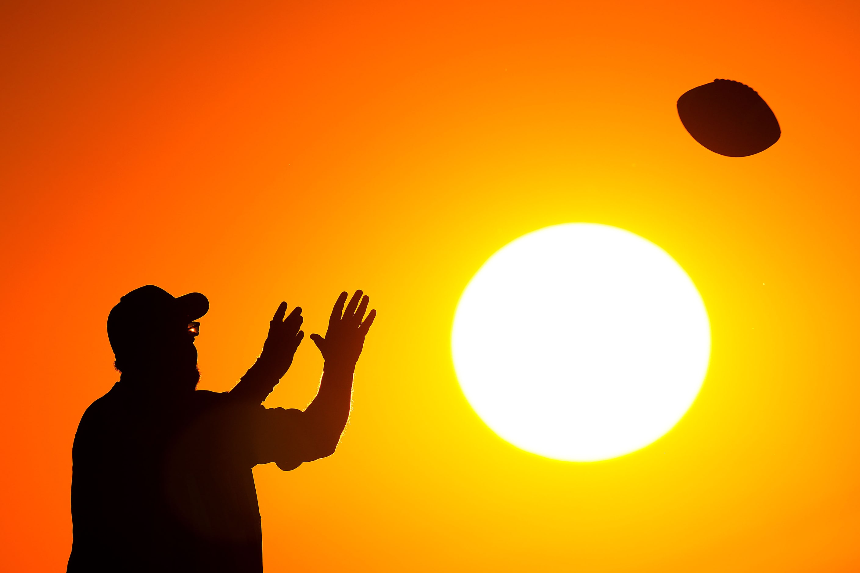 An official reaches for a ball tossed back to the line of scrimmage as the sun sets during...