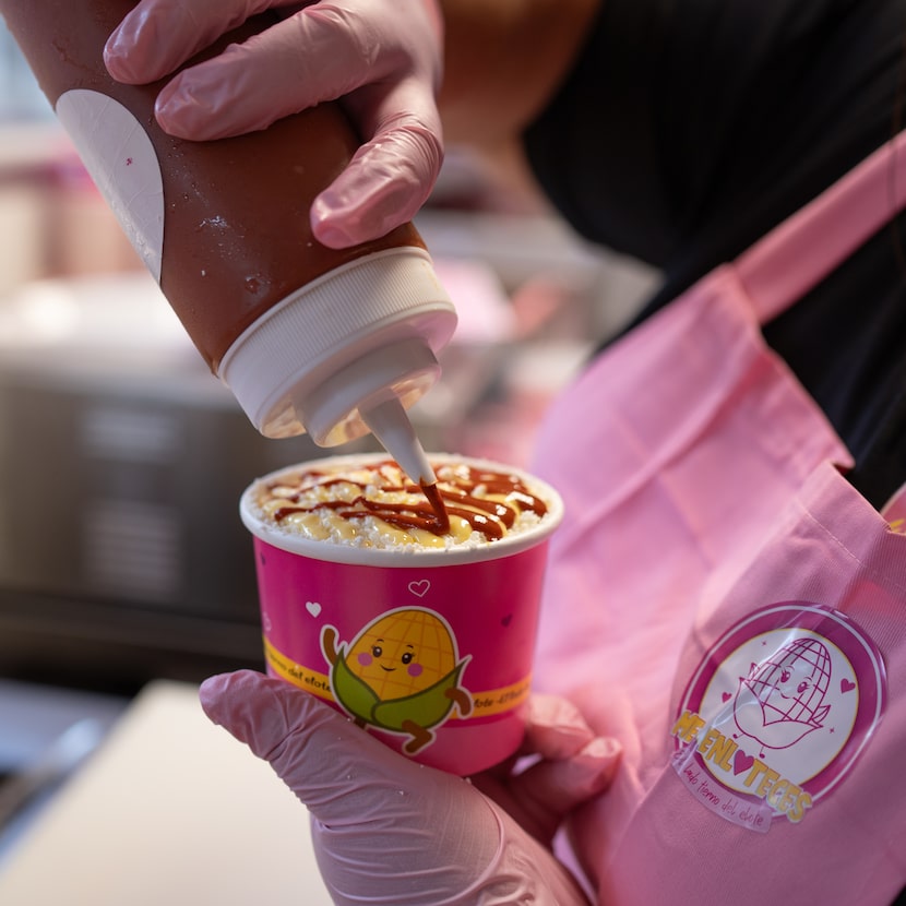 Aidee Del Villar, owner of Me Enloteces, prepares a cup of elote inside her all-pink stand...