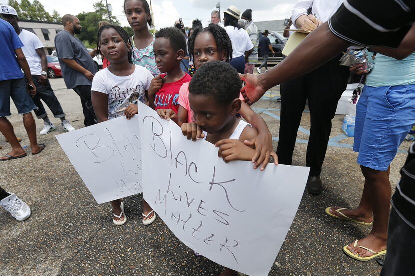 Children hold signs reading "Black Lives Matter" outside the Triple S convenience store in...