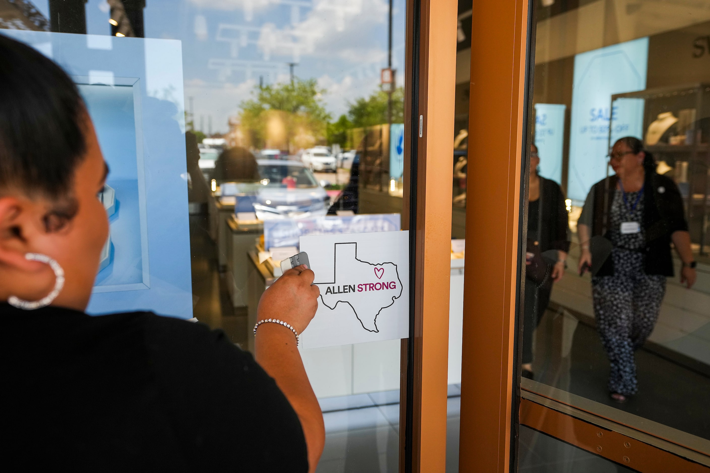 Workers install a decal reading “Allen Strong” on the window at the Swarovski  store at the...