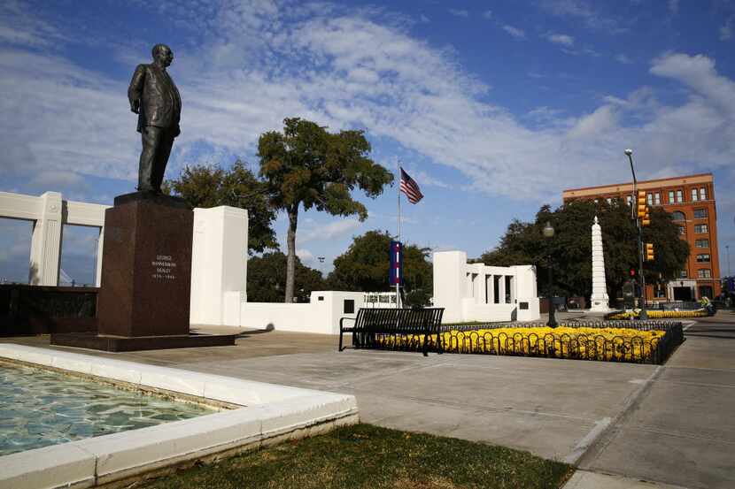 The 12-foot George Bannerman Dealey statue is mounted on a tall, red granite plinth. The...