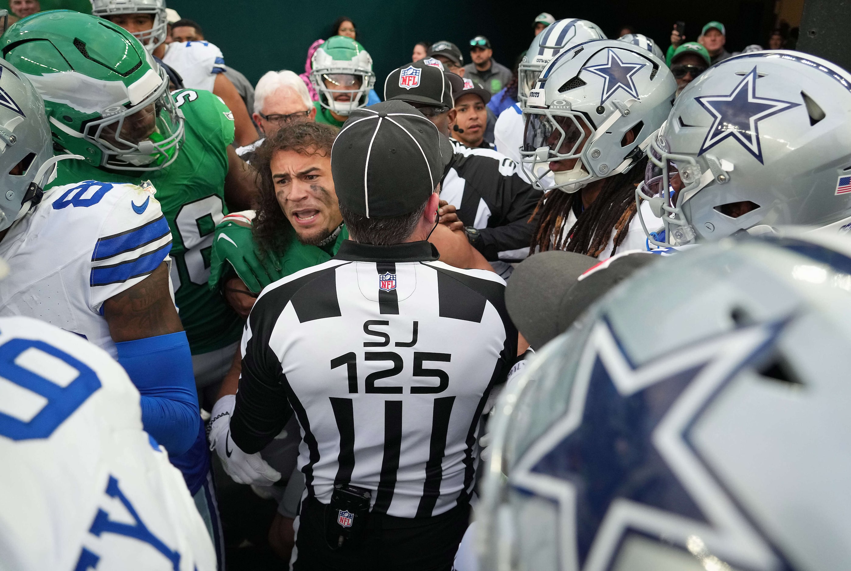 Side judge Chad Hill (125) tries to separate Philadelphia Eagles safety Sydney Brown...