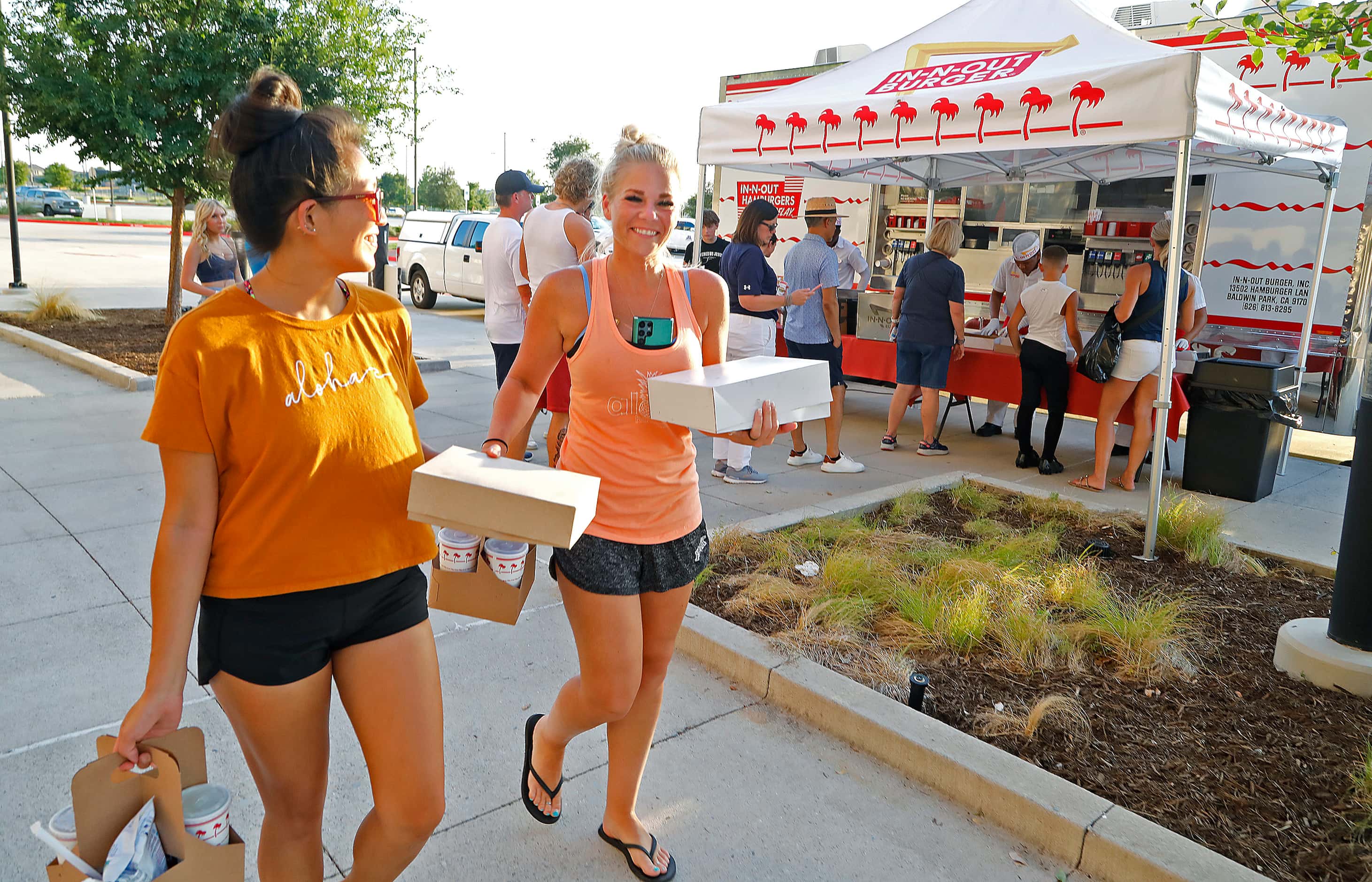 Ali Bailey (left) and Bristyn King pick up food from the In-N-Out food truck to eat while...
