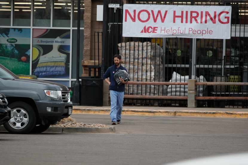 A shopper heads out of an Ace Hardware store past a sign advertising for workers during a...