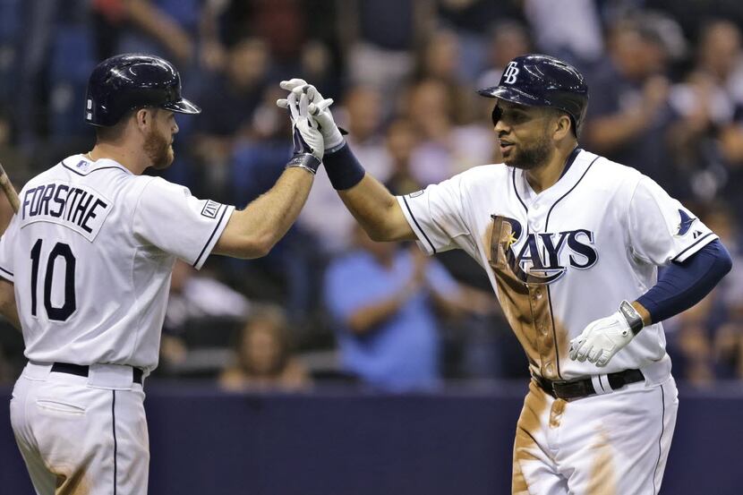 Tampa Bay Rays' James Loney, right, high fives on-deck batter Logan Forsythe after his home...